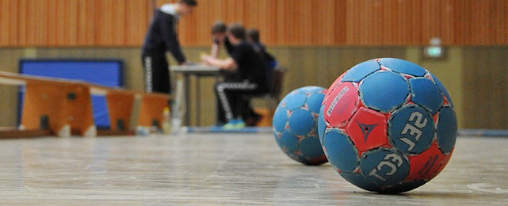 Handball Trainingsball online kaufen im Kübler Sport Onlineshop Mehrere Handball Trainingsbälle verschiedener Größen und Farben für Schule, Verein und Training auf einem Spielfeld
