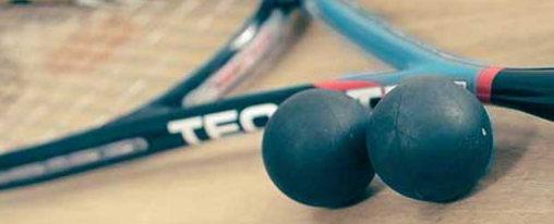 Verschiedene Squashbälle für Training und Wettkampf, passend für unterschiedliche Spielniveaus, auf einem Spielfeld platziert