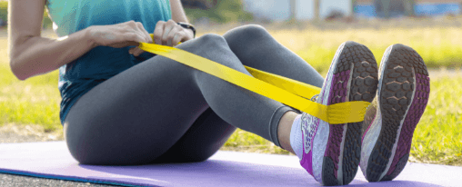 Gymnastikband online kaufen: Vielseitiges Trainingsgerät für Fitness und Therapie bei Kübler Sport Frau trainiert mit Gymnastikband bei Fitnessübungen im Studio
