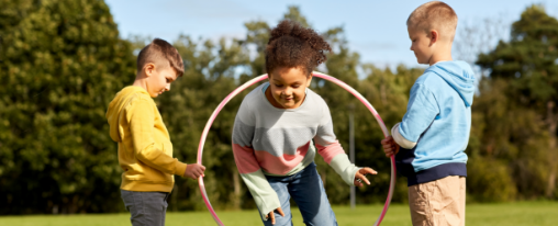 Hula Hoop Reifen online kaufen im Kübler Sport Onlineshop Kinder spielen mit Hula Hoop Reifen bei einem Freizeitspiel im Freien