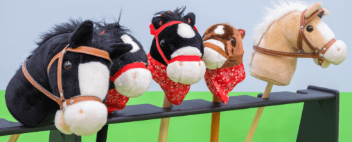 Kinder und Erwachsene beim Freizeitspiel mit einem Hobby Horse auf einer Wiese