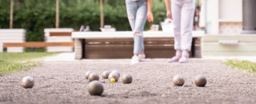 Mehrere Boule Kugeln mit Zielkugel auf einem sandigen Spielfeld als Freizeitspiel