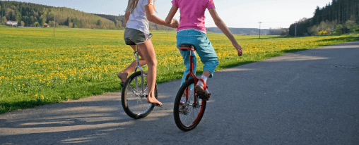 Kinder und Erwachsene fahren Einrad bei Freizeitspielen auf einem Sportplatz