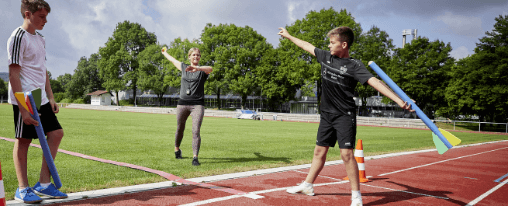 Schüler und Lehrerin auf dem Sportplatz mit Wurfraketen