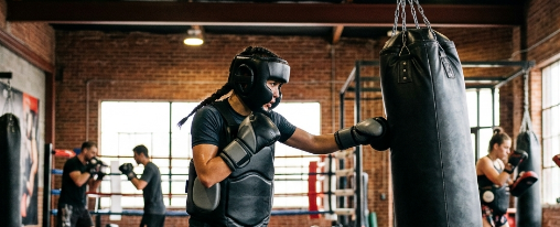 Kampfsportler tragen Schutzausr&uuml;stung wie Kopfschutz, Tiefschutz, Brustschutz und Schienbeinschoner beim Training