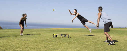Spikeball online kaufen im Kübler Sport Onlineshop Zwei Teams spielen Spikeball als Freizeitspiel auf einer Wiese mit Netz und Ball