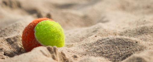 Zwei Sportler stehen mit Schl&auml;ger und Ball auf einem Beach-Tennis-Platz im Sand und pr&auml;sentieren Beach Tennis Ausr&uuml;stung