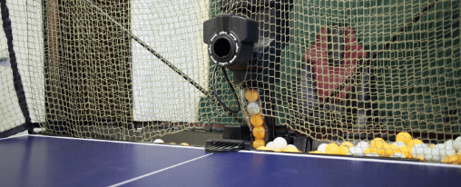 Vielf&auml;ltiges Tischtennis Zubeh&ouml;r f&uuml;r Racketsportler, wie Schl&auml;ger, B&auml;lle und Netze, auf einer Tischtennisplatte im Einsatz