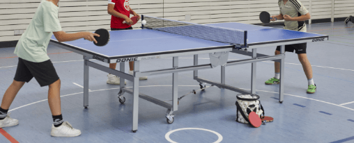 Klappbare Tischtennisplatte online kaufen im Kübler Sport Onlineshop Klappbare Tischtennisplatte mit rollbarem Untergestell und Netz beim Einsatz im Sportverein