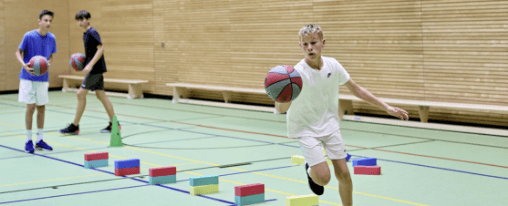 Basketball-Ausrüstung kaufen Basketballkorb mit Basketball perspektivisch von unten fotografiert mit Himmel