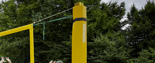 Beachvolleyball-Pfosten im Kübler Sport Onlineshop kaufen Beachvolleyball-Pfosten auf einem Beachvolleyballfeld mit gespanntem Netz, Court-Lines und Schutzpolstern – geeignet für Teamsport, Training und Wettkampf