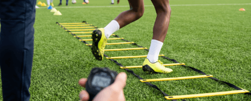 Mehrere Personen nutzen eine Koordinationsleiter beim Training im Verein auf dem Sportplatz
