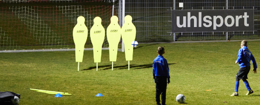 Vereinstraining beim gezielten Torschusstraining mit Trainer und Fußballmannschaft auf dem Sportplatz