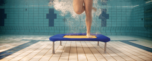 Wassertrampolin online kaufen bei Kübler Sport Mehrere Personen springen auf Wassertrampoline im Schwimmbad beim Aquafitness
