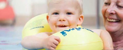 Kinder verschiedener Altersgruppen nutzen Schwimmfl&uuml;gel, Schwimmg&uuml;rtel und weiteres Schwimmzubeh&ouml;r beim Schwimmen im Wasser