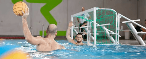 Spielerinnen und Spieler beim Wasserball mit Ball und Tor im Schwimmbecken w&auml;hrend eines Wettkampfs
