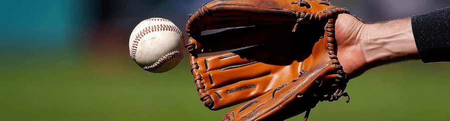 Baseballhandschuh online kaufen im Kübler Sport Onlineshop Teamsport-Spieler mit Baseballhandschuh beim Fangen eines Baseballs auf dem Spielfeld