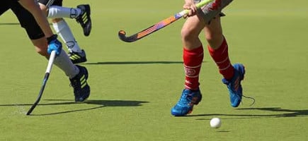 Zwei Hockeyspieler spielen um Hockeyball auf einem Hockeyfeld