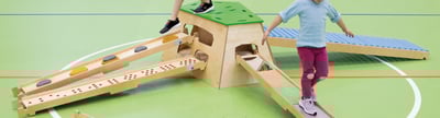 Kinder laufen auf einer mobilen Bewegungslandschaft in einer Turnhalle