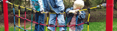 Drei Kinder klettern auf einem bunten Outdoor Kletternetz