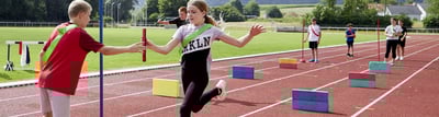 Leichtathletiktraining mit Kindern in Gruppen mit grünen und roten Mannschaftsbändern