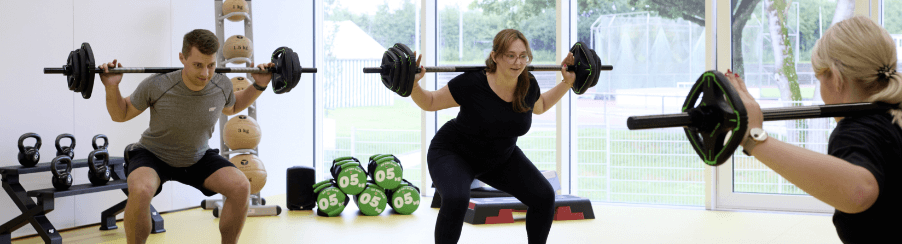 Personen beim Bodypump-Training mit Langhanteln und Gewichten