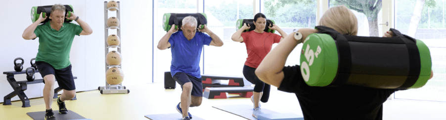 Gruppe trainiert mit Gewichtssäcken auf Gymnastikmatten – Funktionelles Training für Kraft und Ausdauer.