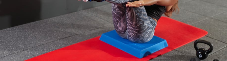 Frau trainiert auf einem Balance Pad und einer Fitnessmatte