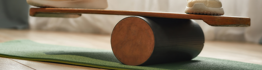 Balance Board aus Holt auf einer Holzrolle auf einer Fitnessmatte