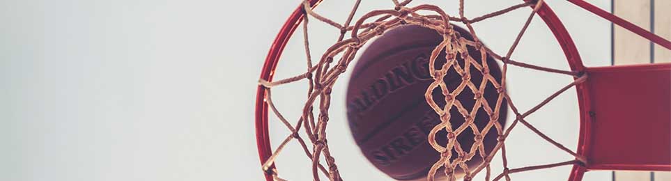 Basketballkorb mit Basketball perspektivisch von unten fotografiert mit Himmel