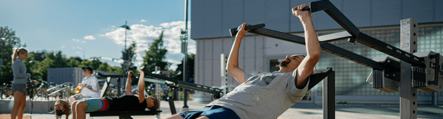 Outdoor Fitnessgeräte im Einsatz in einem Park, ideal für Ganzkörpertraining und funktionelle Übungen