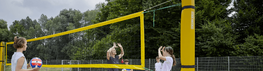 Beachvolleyball-Pfosten auf einem Beachvolleyballfeld mit gespanntem Netz, Court-Lines und Schutzpolstern – geeignet für Teamsport, Training und Wettkampf