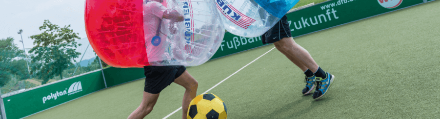 Teamsport-Gruppe spielt Bubble Soccer mit Bubble Balls in einer Sportarena