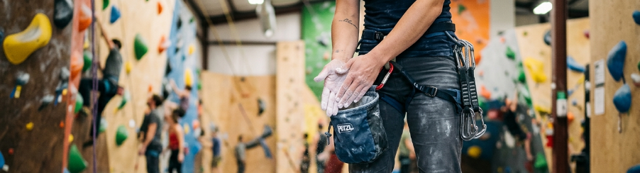 Kletterer benutzt Chalk an einer Boulderwand für mehr Griffigkeit und trockene Hände