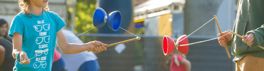 Personen spielen mit Diabolo als Freizeitspiel – Jonglage mit Handstäben und Doppelkegel im Freien