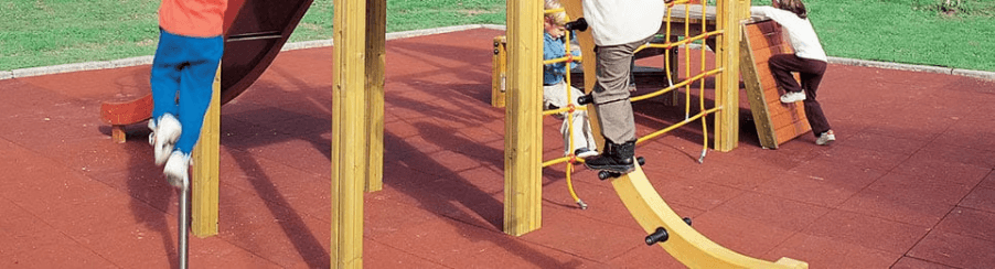 Fallschutzplatten auf einem Spielplatz unter verschiedenen Spielplatzgeräten wie Schaukeln und Rutschen