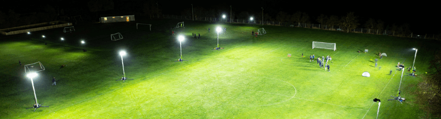 Flutlichtanlage auf einem beleuchteten Fußballplatz bei Nacht mit klar sichtbaren Flutlichtmasten und Spielfeld