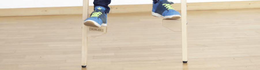 Zwei Kinder beim Spielen mit Holzstelzen im Garten – Freizeitspiele mit stabilen Holzstangen und rutschfesten Gummikappen