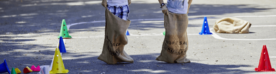 Zwei Kinder spielen Sackhüpfen auf dem Schulhof  mit Markierhütchen