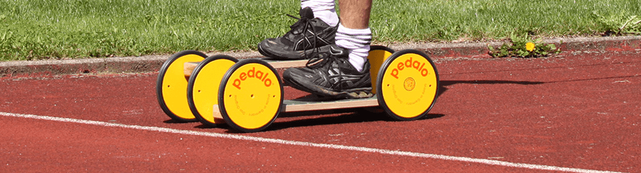 Mehrere Kinder fahren auf Pedalroller im Freien auf einem Spielplatz