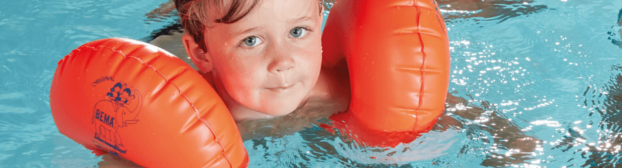 Kinder mit Schwimmhilfen beim Schwimmenlernen im Wasser
