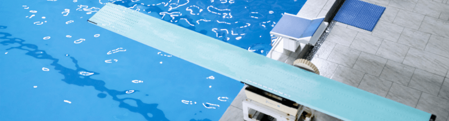 Wassersportler steht vor Sprungbrett am Schwimmbeckenrand für Training und Freizeit im Schwimmbad