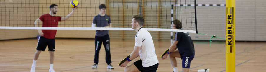 Teamsportgruppe beim Training mit verschiedenen volleyball trainingsgeräten in der Sporthalle