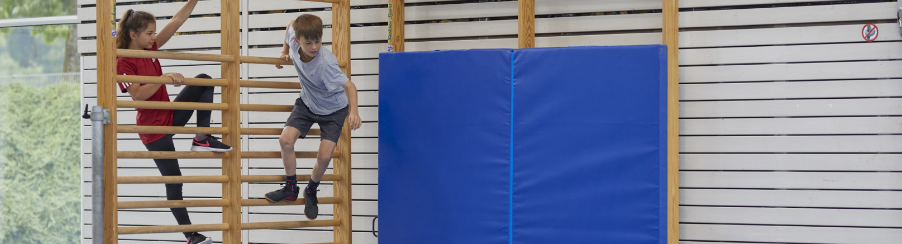 Kinder an einer Sprossenwand aus Holz mit Prallschutzmatte