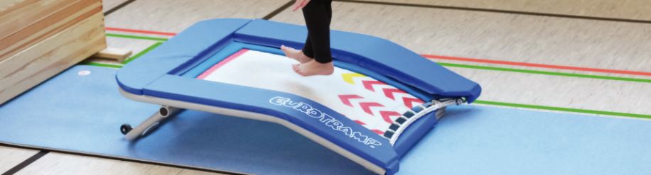 Kind springt auf einem Schultrampolin in einer Sporthalle ab